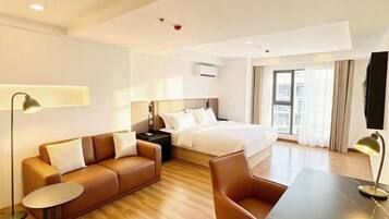 Una habitación de hotel moderna con cama, sofá, mesa de comedor y escritorio.