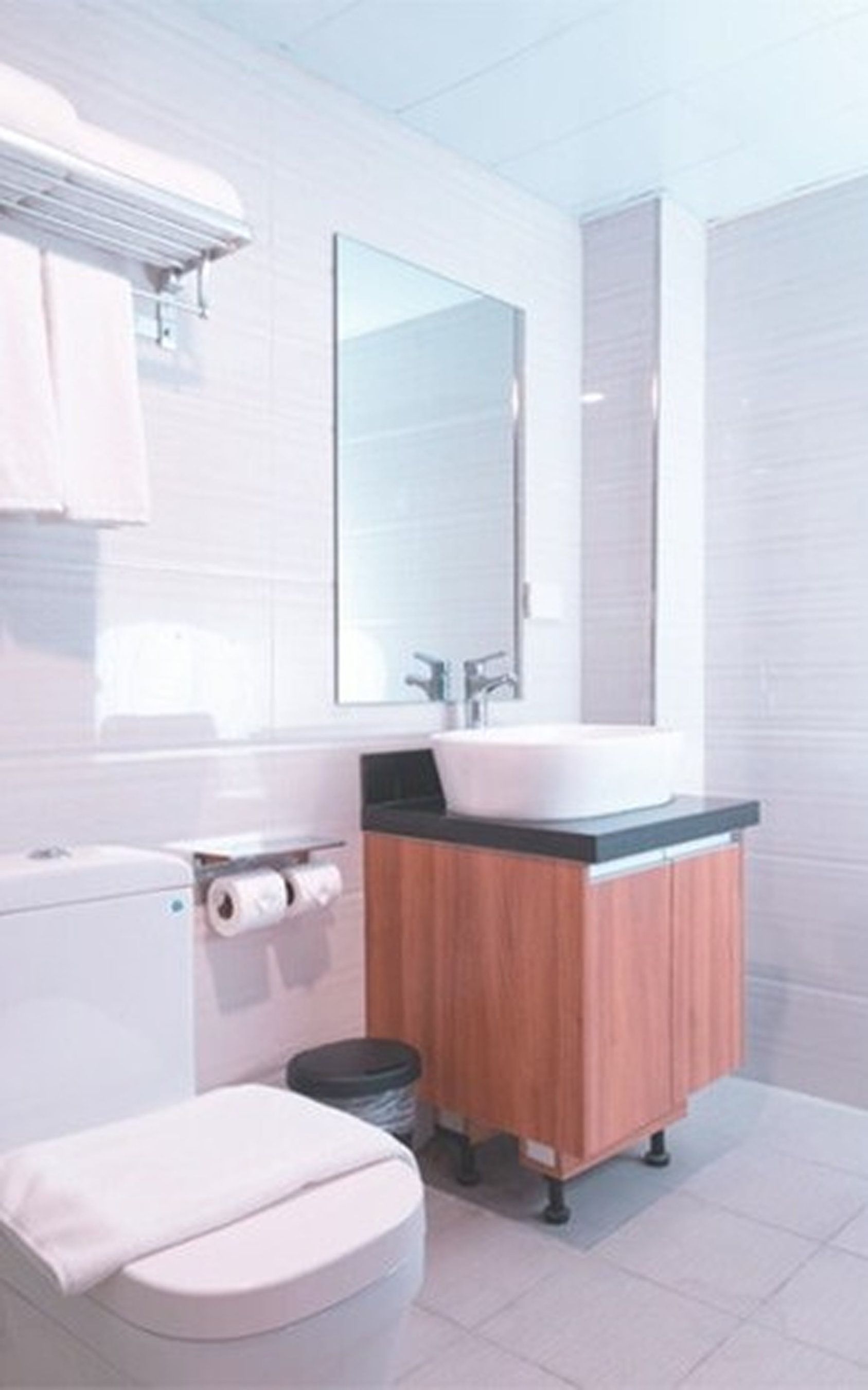 Un baño moderno con inodoro, lavabo y espejo.