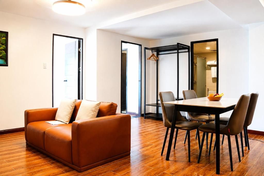 Una sala de estar moderna con un sofá de cuero marrón, una mesa de comedor con sillas y un espejo grande.