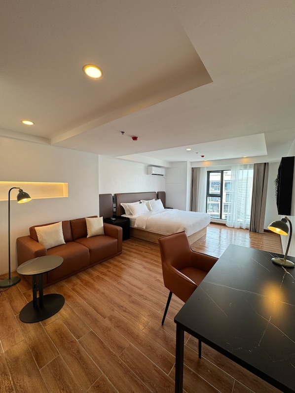 A modern hotel room with a bed, sofa, and a dining table. - W9 Hotel And Resorts (Parañaque)