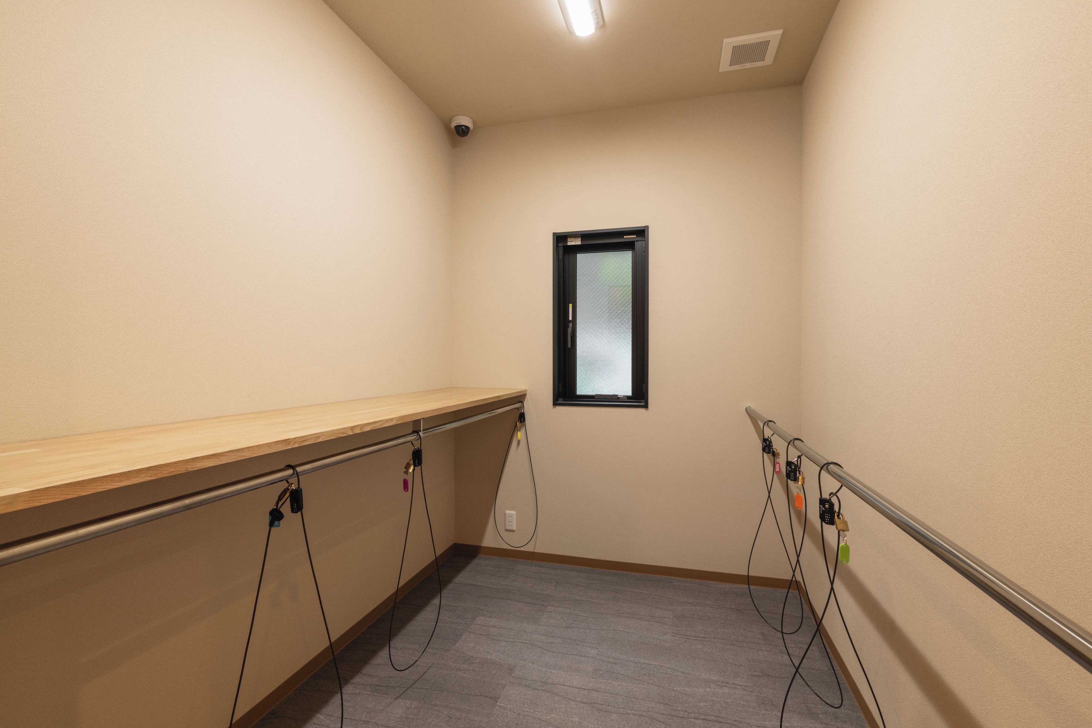 A corridor with a wooden bench, a window, and a security camera.