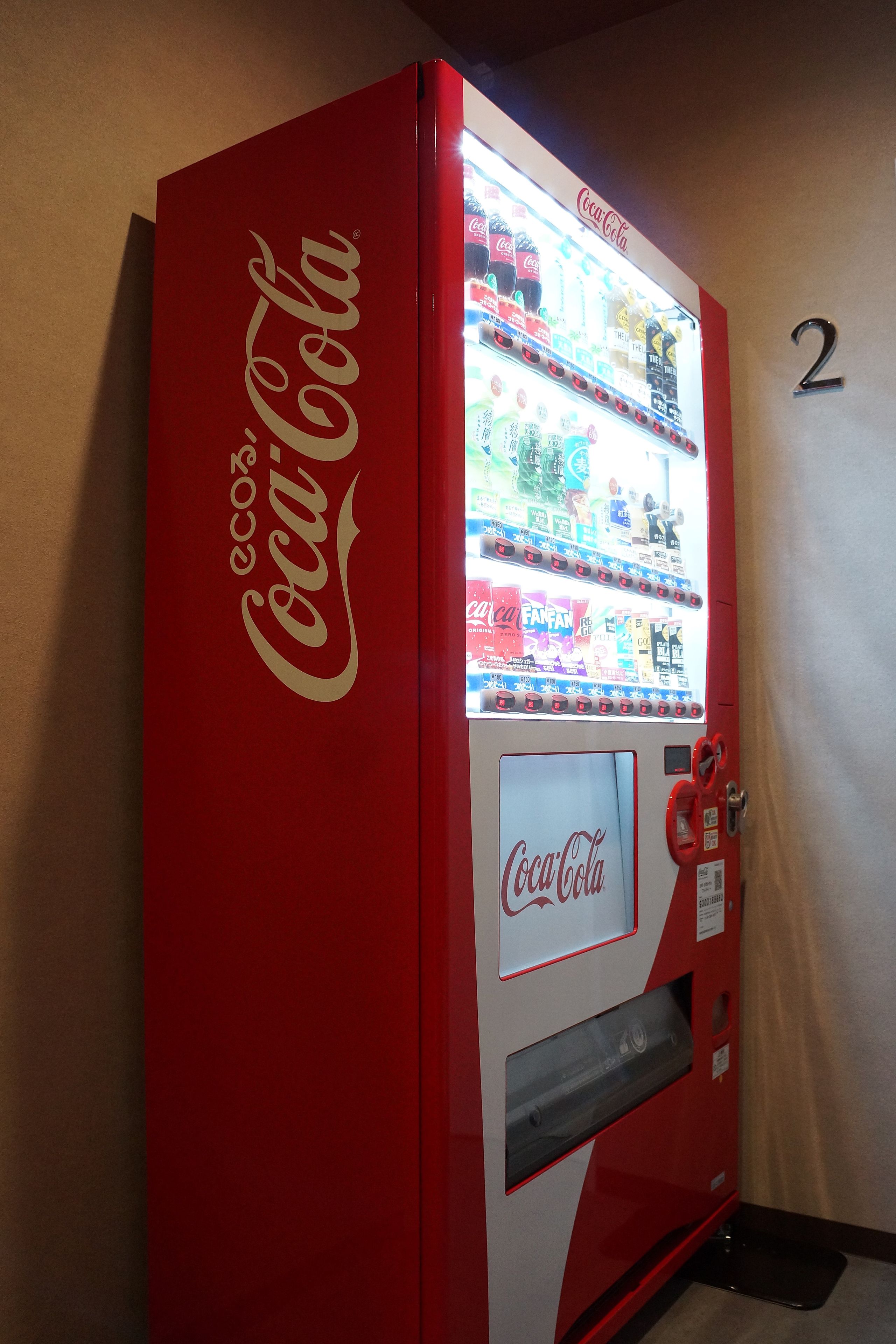 A red Coca-Cola vending machine with a selection of beverages and price tags.