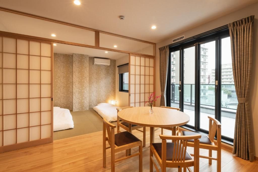 Et traditionelt japansk værelse med tatamimåtter, et lavt bord med stole og en skydedør i shoji-stil.