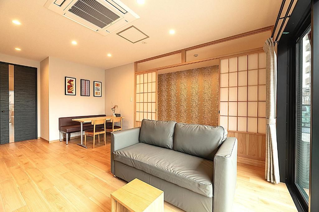 A modern living room with a sofa, a dining table, and a sliding shoji screen.