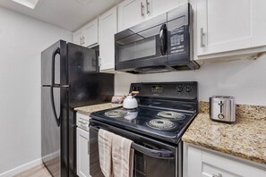 A kitchen with a black refrigerator, a microwave, a stove, and a toaster. - Comfortable Mesa Retreat, 2 Queen Beds, & Pool (Mesa)
