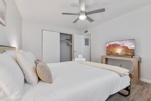 A bedroom with a bed, a ceiling fan, a TV on a wooden stand, and a closet. - Comfortable Mesa Retreat, 2 Queen Beds, & Pool (Mesa)