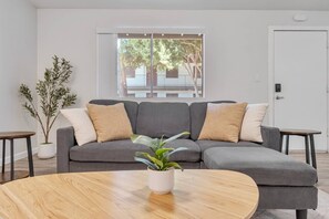A modern living room with a grey sectional sofa, a round wooden coffee table, and a potted plant. - Comfortable Mesa Retreat, 2 Queen Beds, & Pool (Mesa)