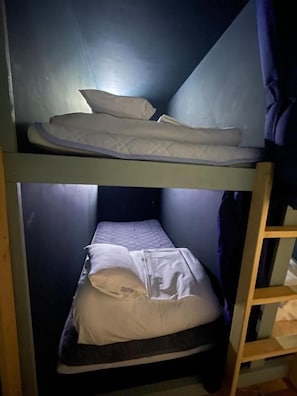 Un letto a castello con due piani, ciascuno dotato di materasso e cuscini.