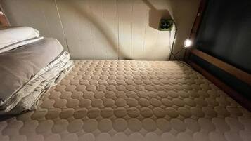 Una cama litera con un colchón que presenta un diseño circular, un cabecero con luz integrada y un enchufe pequeño en la pared.