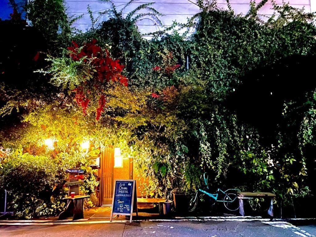 Un área de estar al aire libre con un letrero del Air Osaka Hostel.