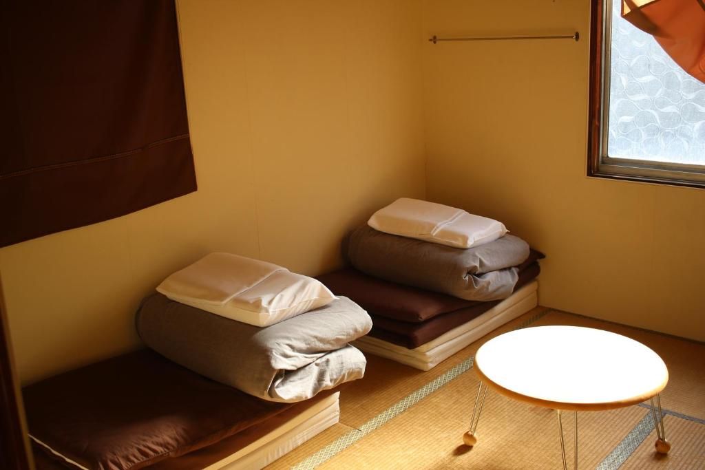 Una habitación pequeña con cama, almohadas, una mesita y una ventana.