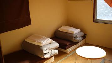 Una habitación pequeña con cama, almohadas, una mesita y una ventana.