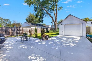 A residential driveway with a garage, a barbecue grill, and a patio with outdoor furniture. - Cozy Cape Cod House, centre of shopping & dinning (Buffalo)