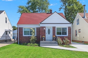 A single-story house with a red roof, white siding, and a front porch with steps leading to a white door. - Cozy Cape Cod House, centre of shopping & dinning (Buffalo)