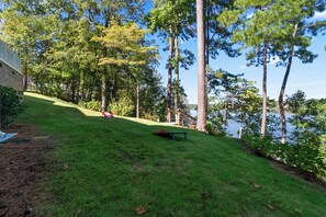 A grassy slope leading to a lake with trees and a bench. - Whispering Pines Manor - Luxury Lake Retreat (Northport)