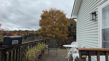 A wooden deck with outdoor furniture, a mailbox, and a view of trees.