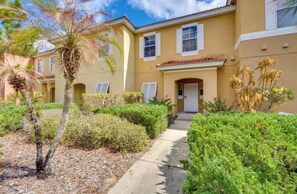 A residential building with a pathway leading to the entrance, surrounded by well-maintained landscaping and palm trees. - Minutes from Magic!!! (Kissimmee)
