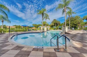A swimming pool with a 4 ft 9 in depth sign, surrounded by palm trees and lounge chairs. - Minutes from Magic!!! (Kissimmee)