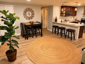 A modern kitchen with a central island, wooden flooring, and a dining area with a round woven rug. - Enjoyable, tropical 3-bedroom house w/ pool and leisure areas in sunny Tampa Bay (Tampa)