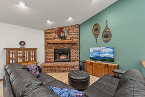 Ein Wohnzimmer mit Kamin, einer Sofagarnitur und einem Fernseher.