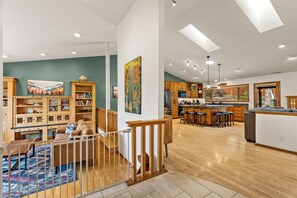 Een ruime woonkamer met een houten trap, een eethoek en een keuken met houten kastjes en een bar.