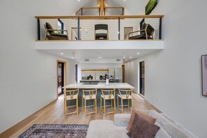 A modern loft-style apartment with a kitchen, dining area, and a balcony with seating.