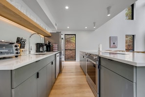 A modern kitchen with a central island, stainless steel appliances, and a wooden countertop.