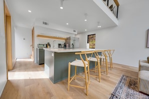 Una cocina moderna con una isla central, taburetes de bar y vistas al exterior.