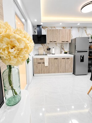 A modern kitchen with white marble countertops, wooden cabinets, and a stainless steel refrigerator. - Carolina Luxe 2BR Escape Near SJU (Carolina)