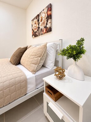 A neatly arranged bedroom with a bed, pillows, a bedside table with a plant, and wall art. - Carolina Luxe 2BR Escape Near SJU (Carolina)