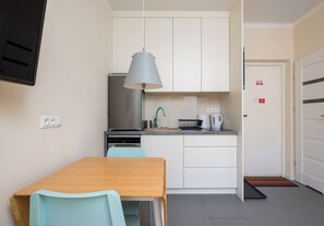 A compact kitchen with a dining table, chairs, a kettle, and a coffee maker. - Park Moczydło Cozy Studio (Warszawa)