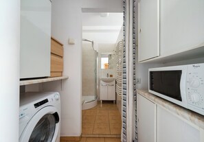 Ein Waschraum mit Waschmaschine, Mikrowelle und Dusche.