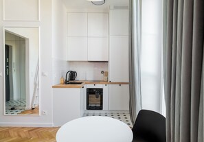 A compact kitchen with white cabinets, a built-in oven, and a small countertop. - Ochota Studio with Mezzanine (Warszawa)