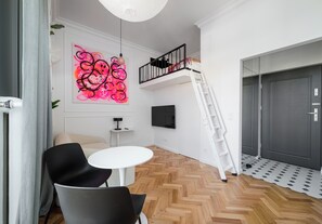 A modern room with a loft bed, a white table, and a black chair. - Ochota Studio with Mezzanine (Warszawa)