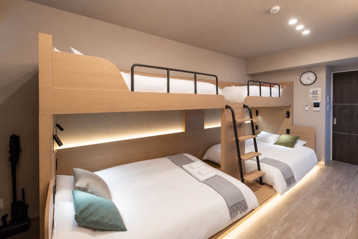A bunk bed room with a wooden headboard, a ladder, and a bedside table with a lamp.