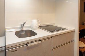 A modern kitchen with a built-in sink, a kettle, and an induction cooktop. - Ocean Dotonbori (Chuo-ku)