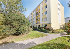 A multi-story residential building with a paved walkway and greenery. - Ochota Green Spot Studio (Warszawa)