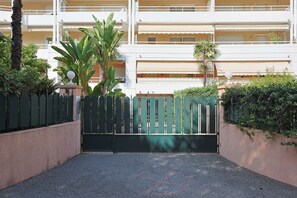 A gated entrance with a paved driveway leading to a multi-story building with balconies. - Upstays Spacious 2BR 100m² with terrace and pool (Cannes)