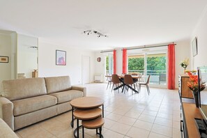 A living room with a sofa, a coffee table, and a dining area with chairs and a table. - Upstays Spacious 2BR 100m² with terrace and pool (Cannes)