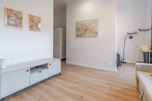 A modern living room with a white cabinet, a large painting, and a floor lamp. - Urban Nest Chic Studio (Katowice)