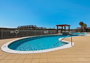 Une piscine entourée d’une clôture, dotée d’un poste de surveillance pour les sauveteurs et agrémentée d’un kiosque.