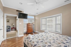 A bedroom with a bed, dresser, and a television on the wall. - Sleeps 18 | 8BR | Steps To The Beach | Pool |UR (Myrtle Beach)