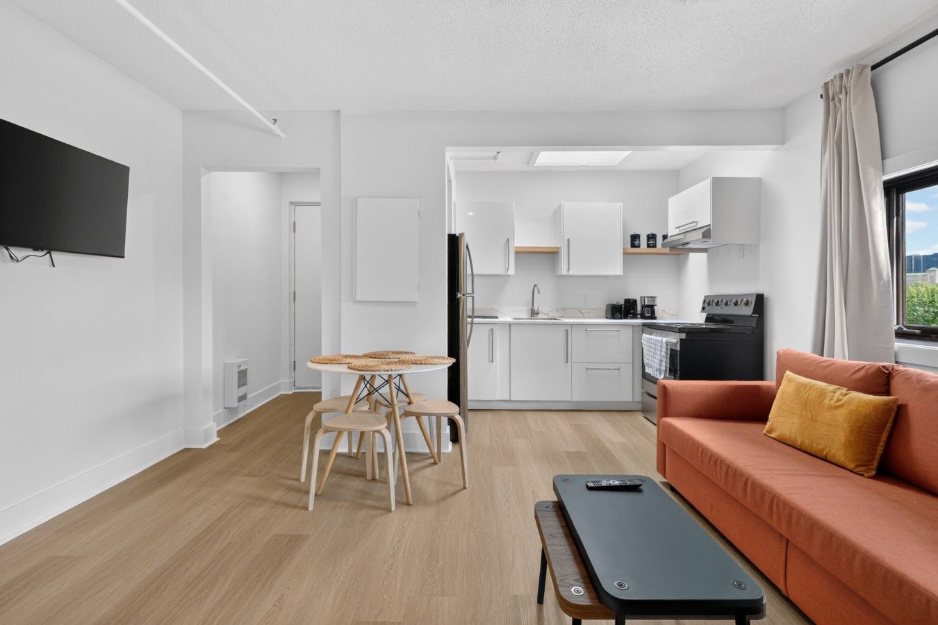 Una sala moderna con un sofá, una mesa de centro y una mesa de comedor con sillas.