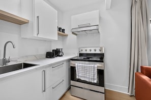 A compact kitchen with a sink, coffee maker, and stove. - Spacious Studio Suite in Downtown Gatineau Sleeps 4 (Gatineau)