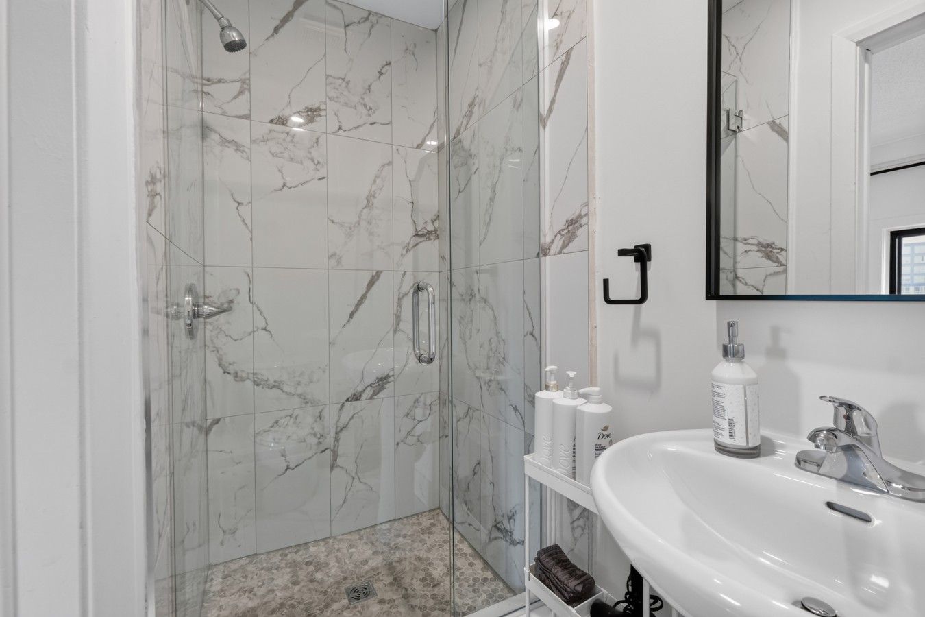 A bathroom with a shower, a sink, and a mirror.