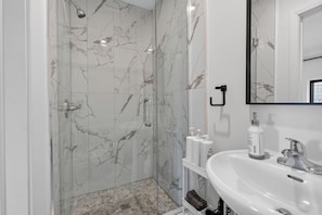 A bathroom with a shower, a sink, and a mirror. - Spacious Studio Suite in Downtown Gatineau Sleeps 4 (Gatineau)