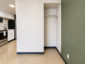 A kitchen with white cabinets, a black refrigerator, and a tiled backsplash. - The Foundry Studio | Downtown Retreat St10 (Birmingham)