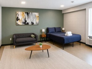 A room with a sofa, a bed, a coffee table, and a painting on the wall. - The Foundry Studio | Downtown Retreat St10 (Birmingham)