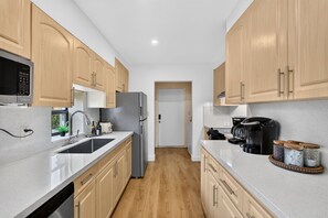 Eine moderne Küche mit Holzausstattung, einem Edelstahlkühlschrank, einer Kaffeemaschine und einem Spülbecken.