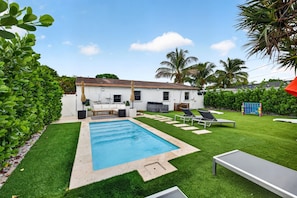 A backyard with a swimming pool, a barbecue area, and a seating area with lounge chairs. - Casa Palma Heated Pool Hot Tub Games (Fort Lauderdale)